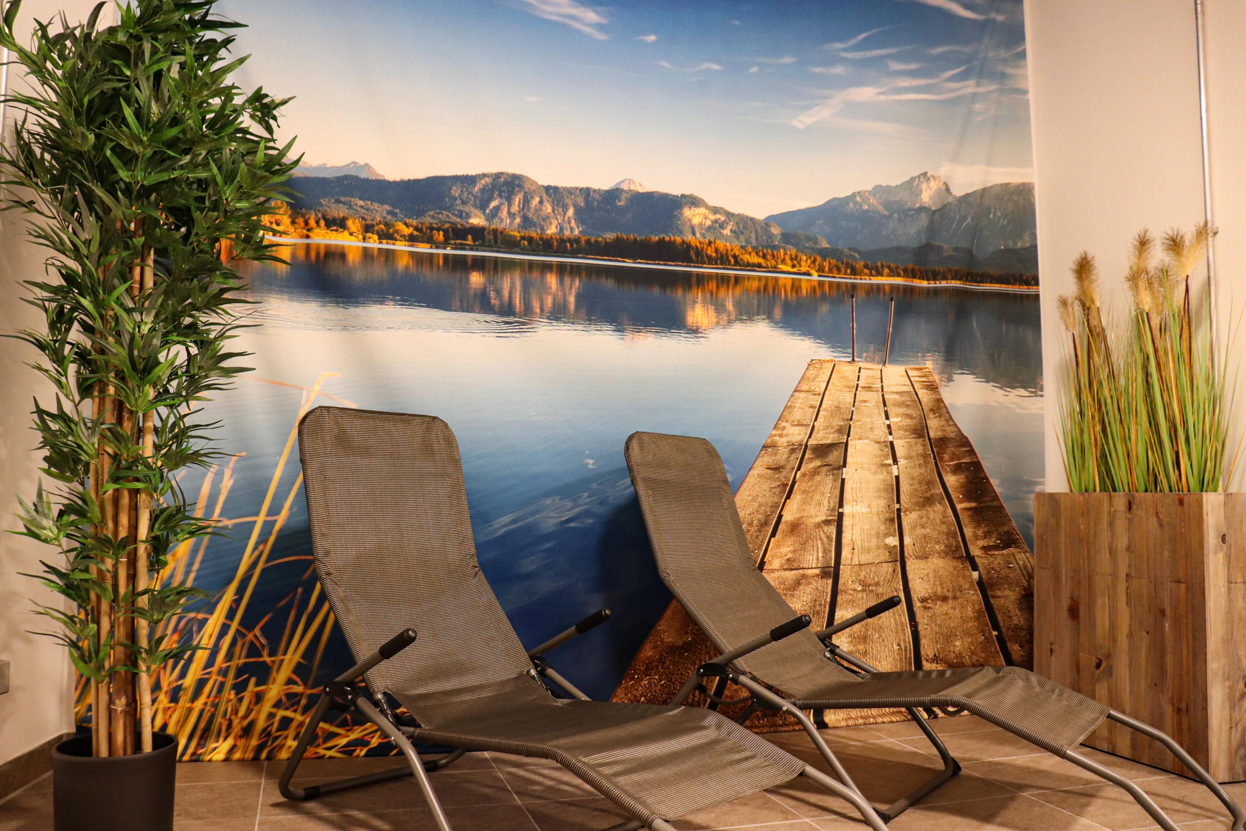 Der Ruheraum des Saunabereiches mit einem Wandbild mit Bergen und See im trendic hotel.