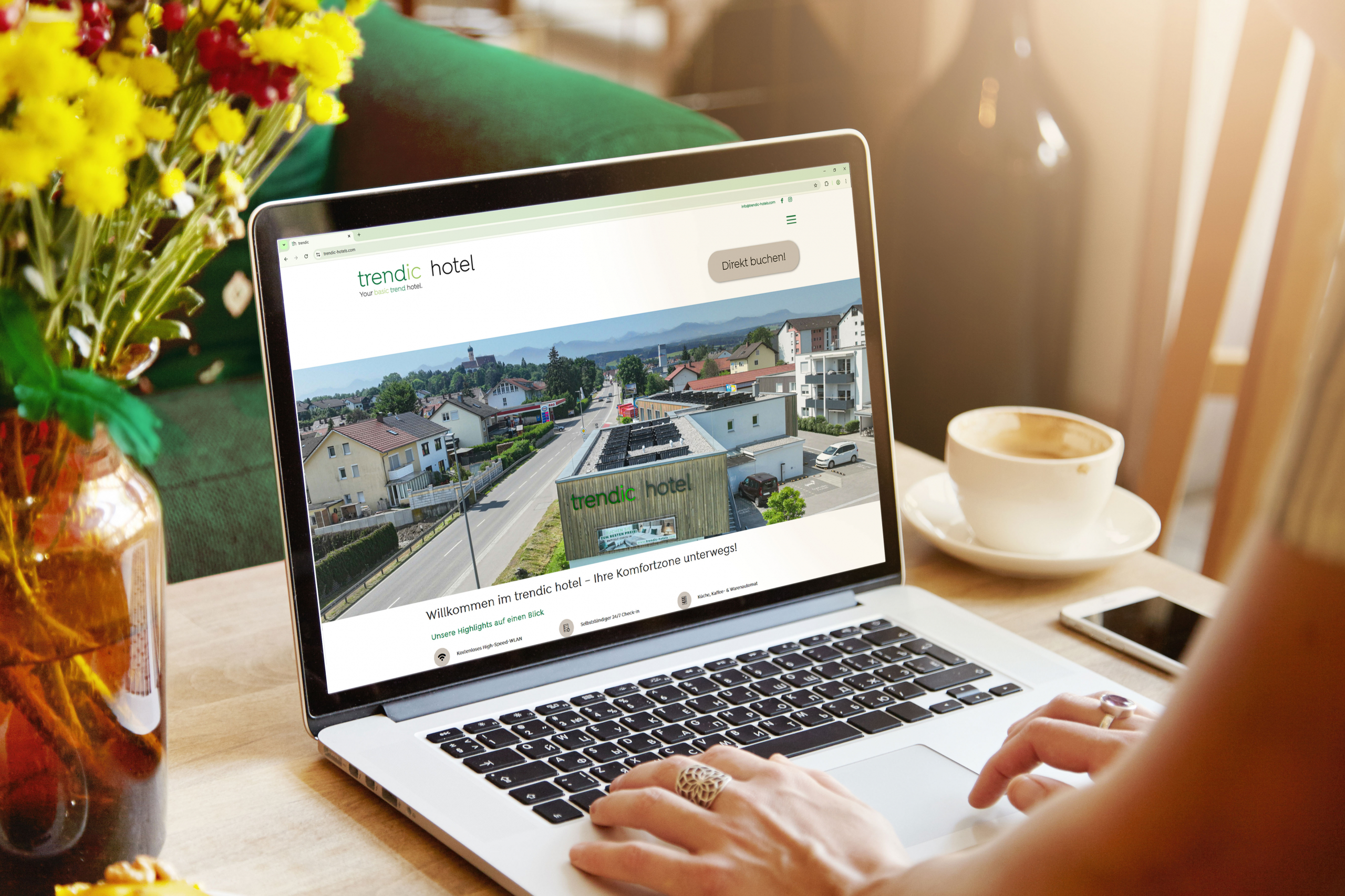 Eine Frau hat ihre Hände auf der Tastaur ihres Laptops und schaut auf die Startseite der trendic hotel Website.