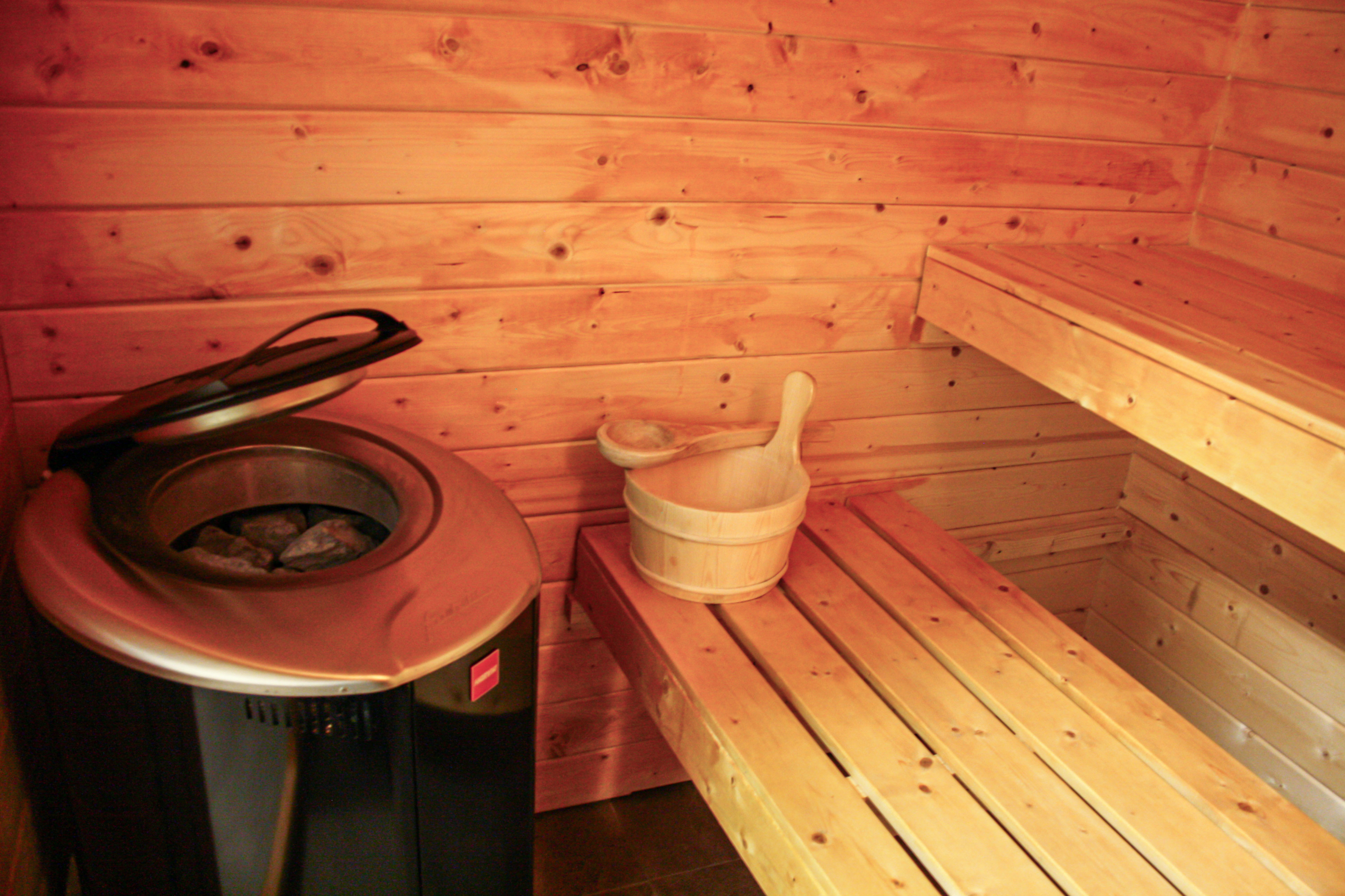 Holzbänke und ein Saunaofen - die Ausstattung der Sauna im trendic hotel.